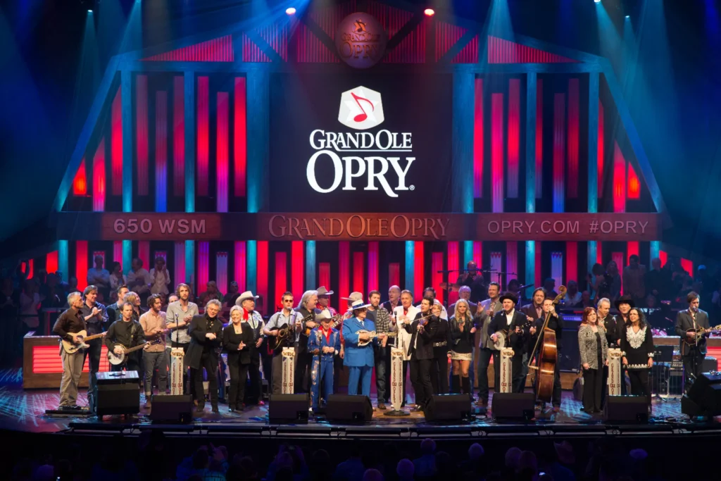 Exterior view of the iconic Grand Ole Opry building in Nashville, Tennessee, with a blue sky and clouds in the background.