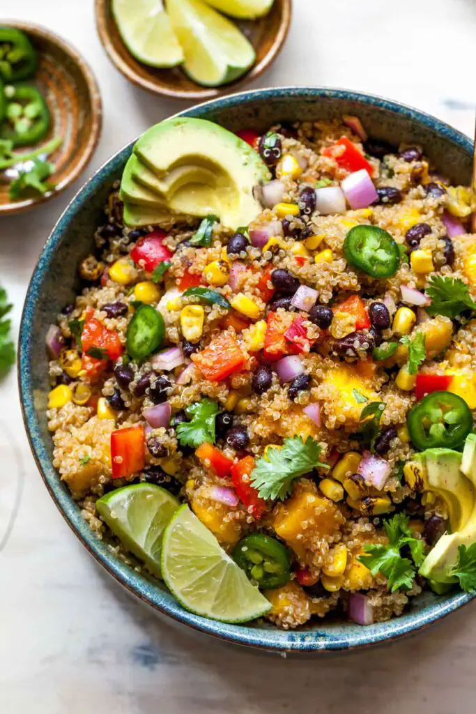 A bowl filled with vibrant mango avocado quinoa salad, featuring ripe mango chunks, creamy avocado slices, cooked quinoa, and fresh cilantro, a perfect summer dish.