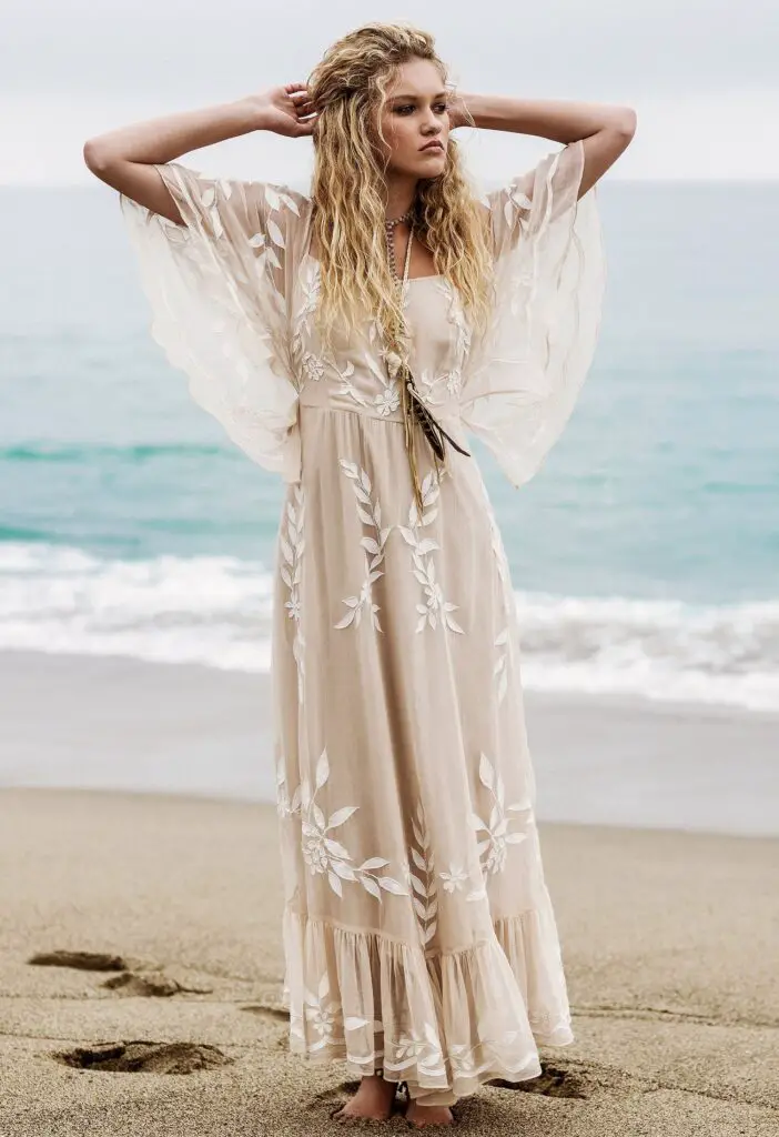 A woman standing in elegant maxi wedding dress with intricate lace detailing.