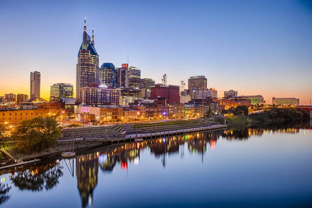 A vibrant street scene in Nashville's Gulch neighborhood, showcasing modern architecture, colorful murals, and bustling activity.